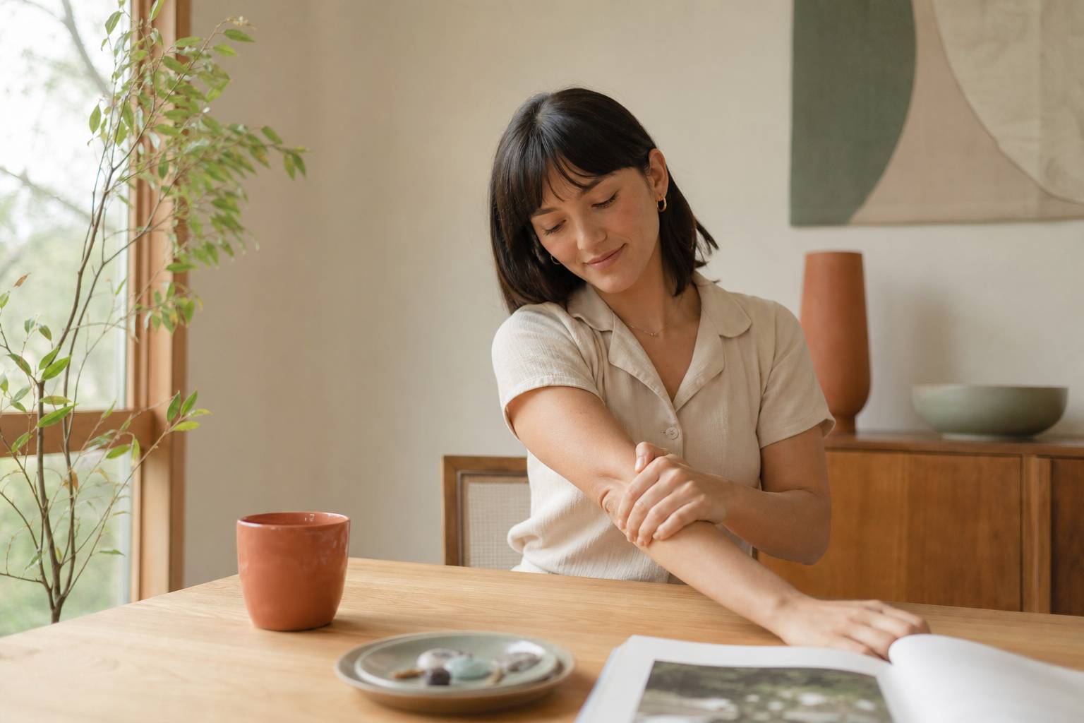 Personne se massant les avant-bras assise a une table